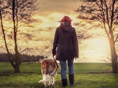 Eine Frau geht mit ihrem Hund gassi.